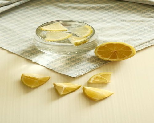 Vaso de agua con limón y frutas de temporada en una mesa